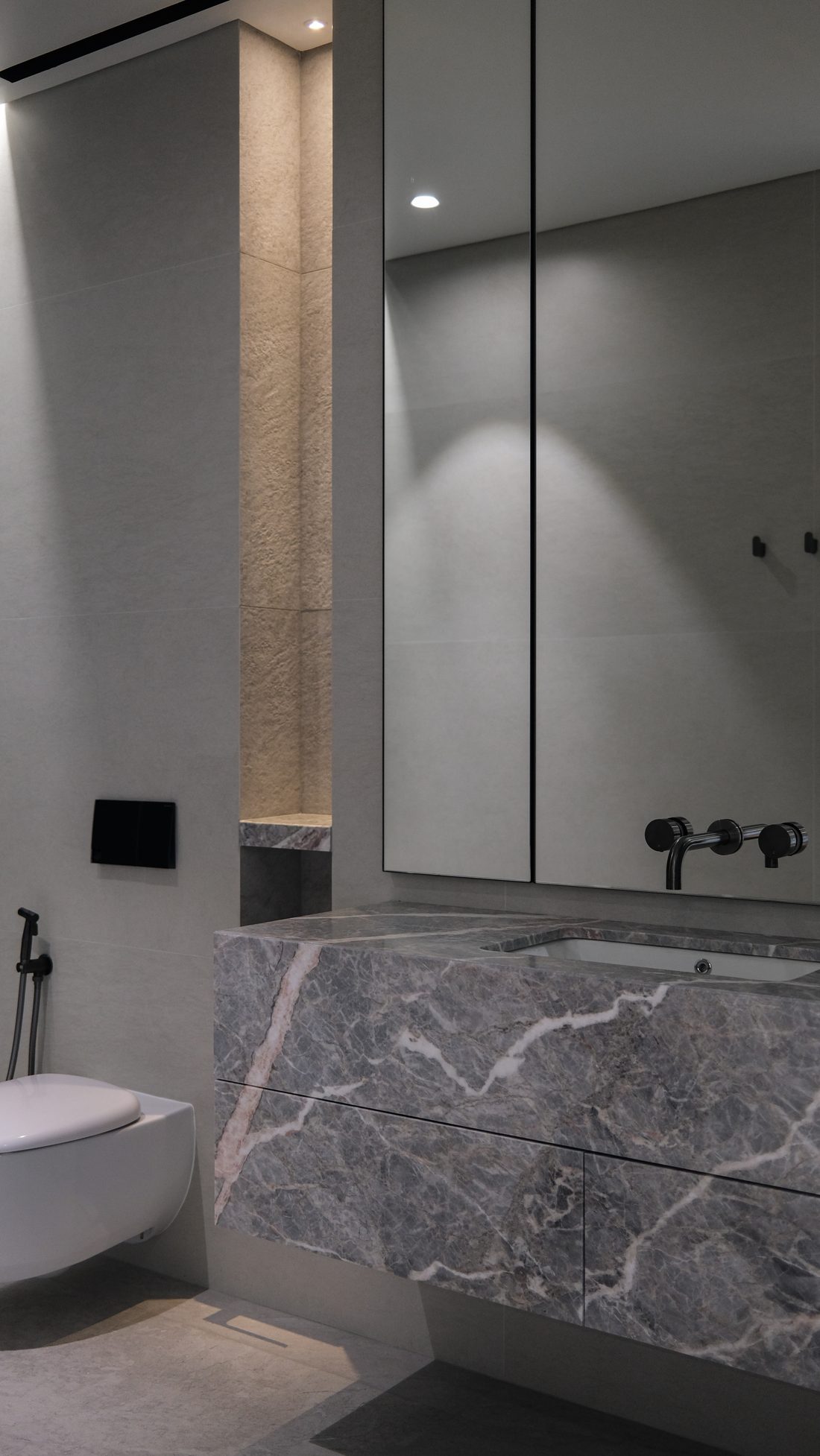 An ensuite — grey-marble vanity, mirrored cabinet and a lit stone niche