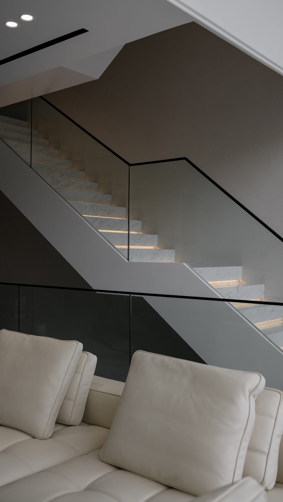 The cantilevered marble stair behind a frameless glass balustrade