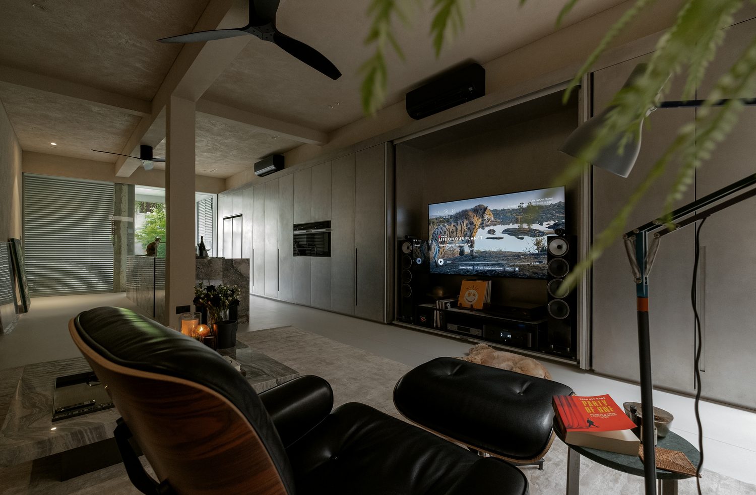 The living room — a media wall and floor speakers, the open kitchen beyond