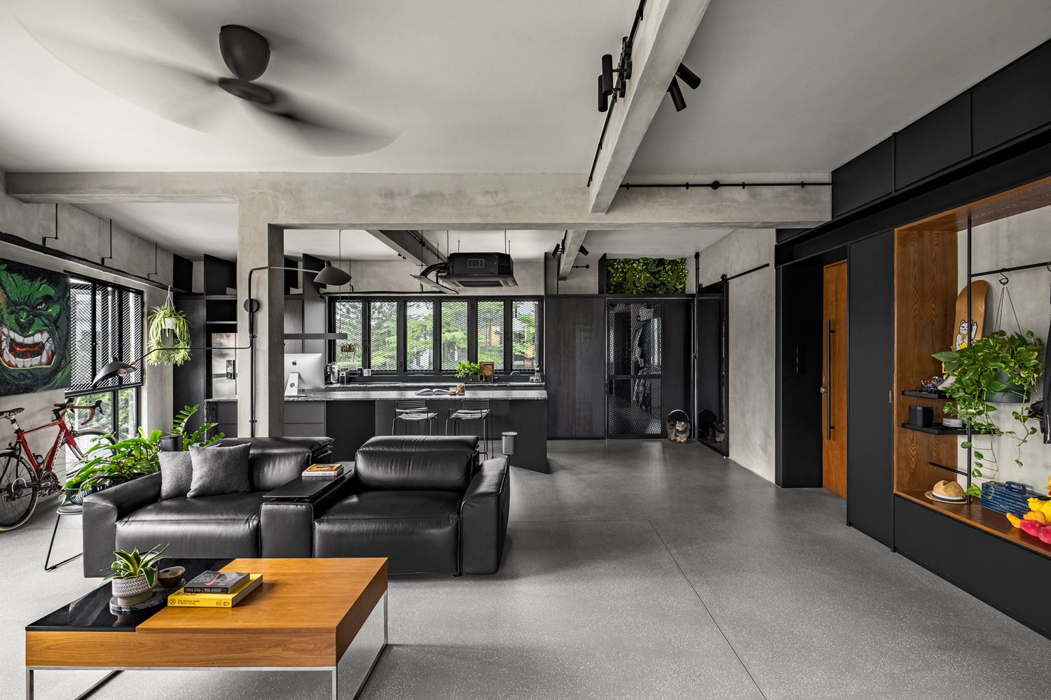 Living and kitchen — leather sofas, a comic mural and a road bike against the concrete shell