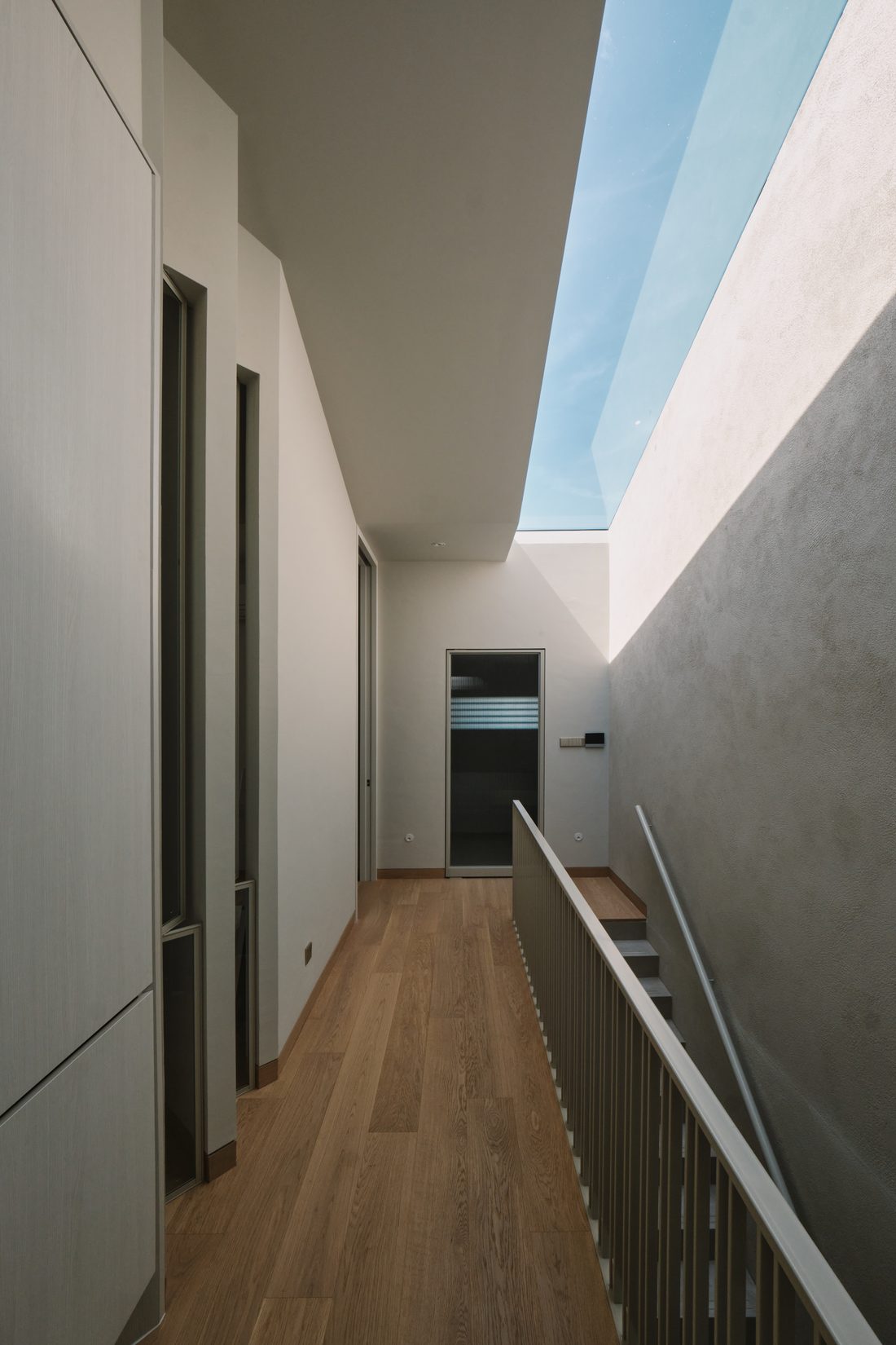 An upstairs landing — oak flooring and a slatted balustrade beneath a long skylight slot