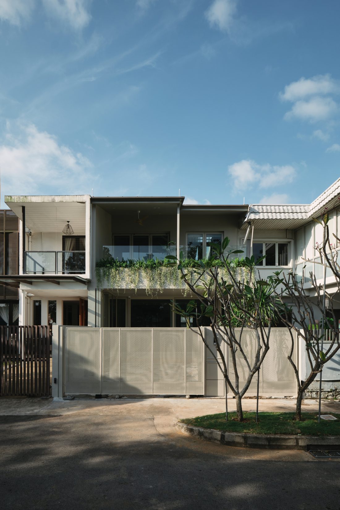 The facade in portrait — upper-balcony planting spilling over board-formed concrete