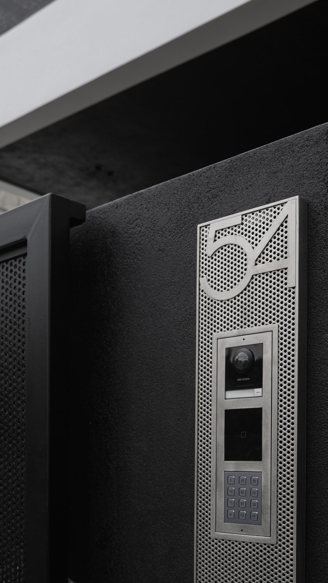 Arrival — a stainless house number set into a perforated black gate