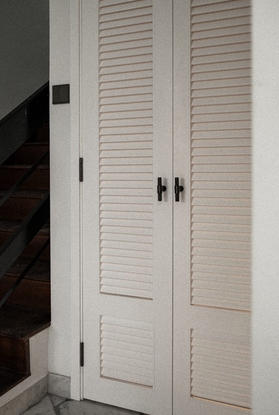 A detail — louvred folding doors beside the timber stair
