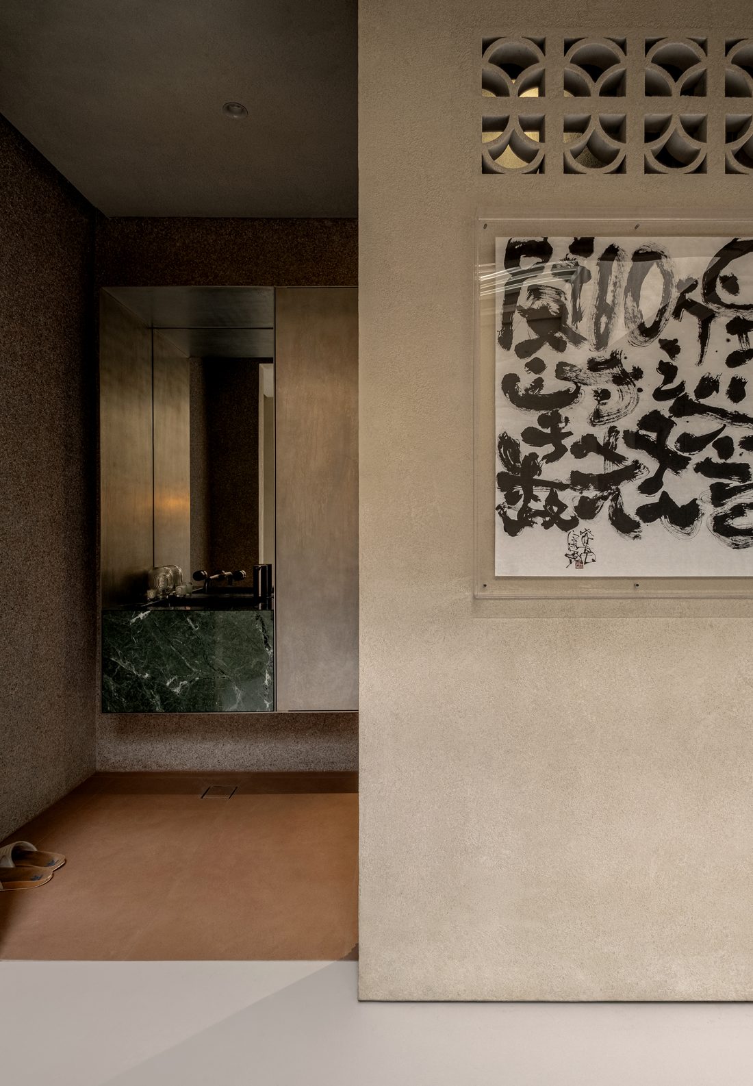 A washroom threshold — green marble basin and ink calligraphy on plaster