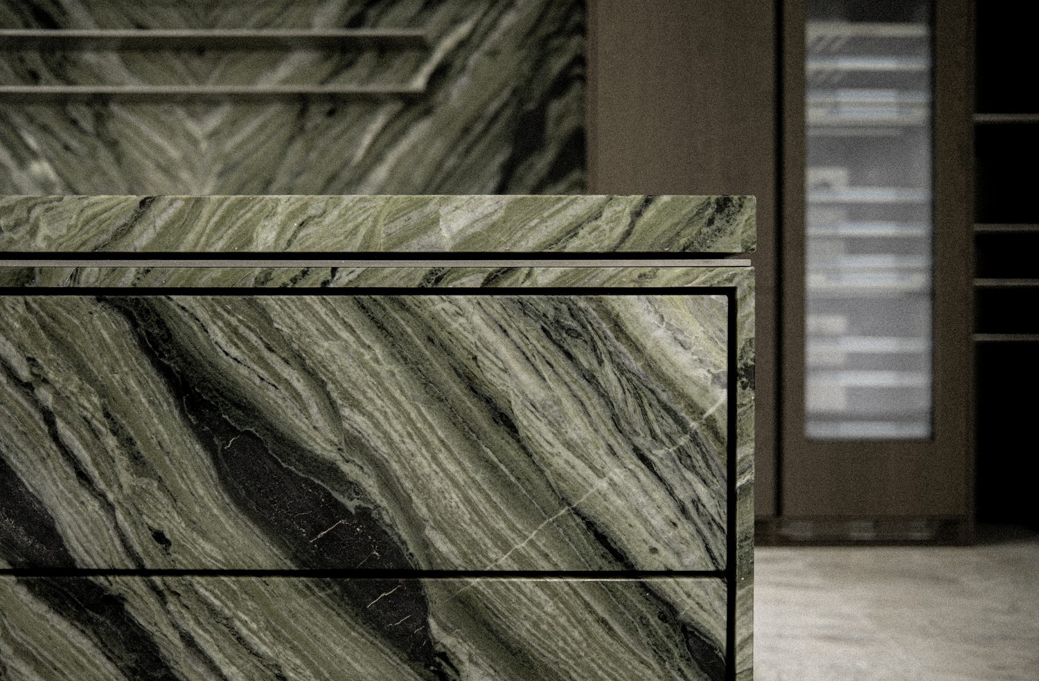 The island — a green-marble waterfall edge meeting warm oak joinery