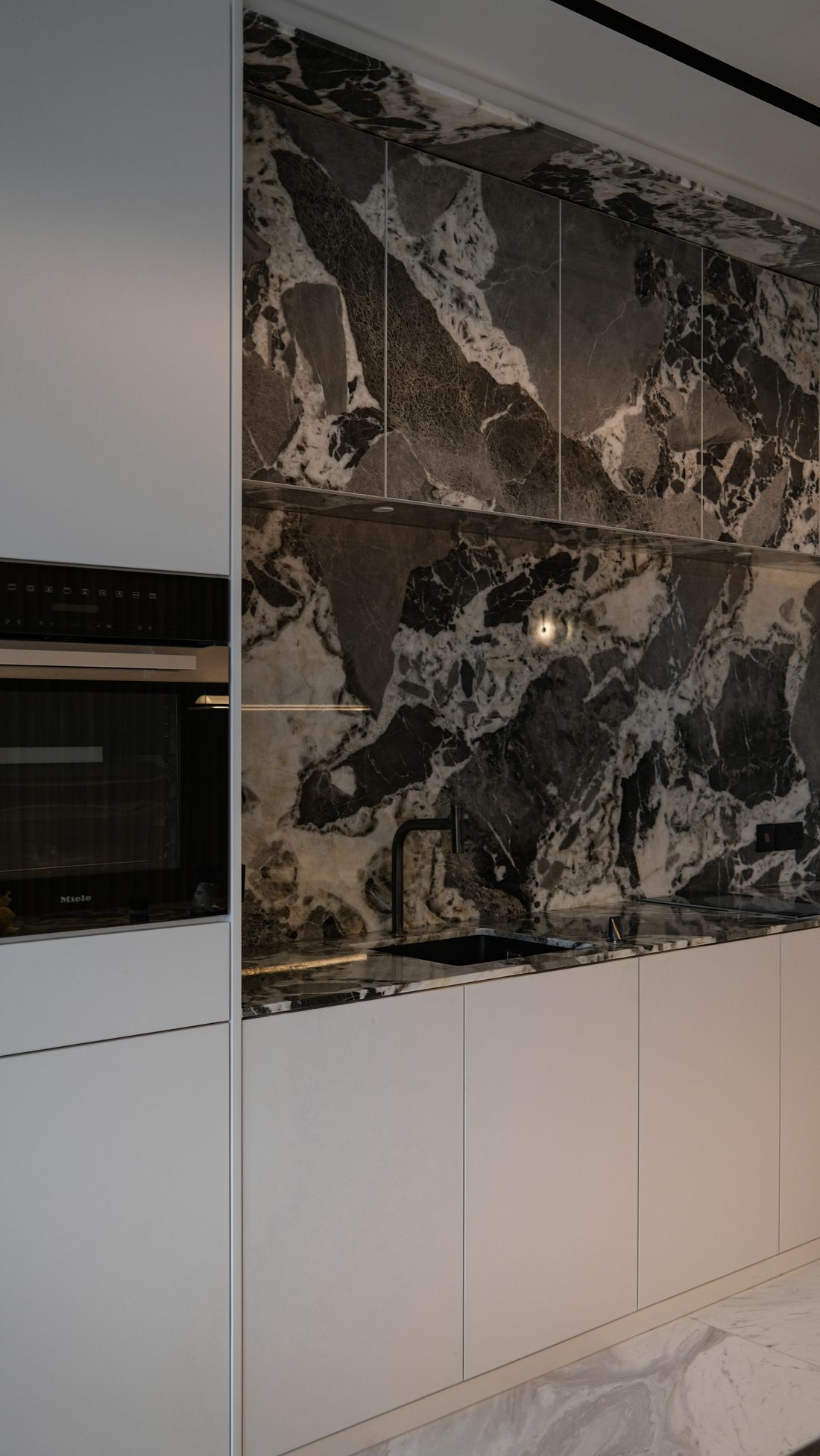 The kitchen — a dramatic grey-and-white marble run with pale handleless cabinetry