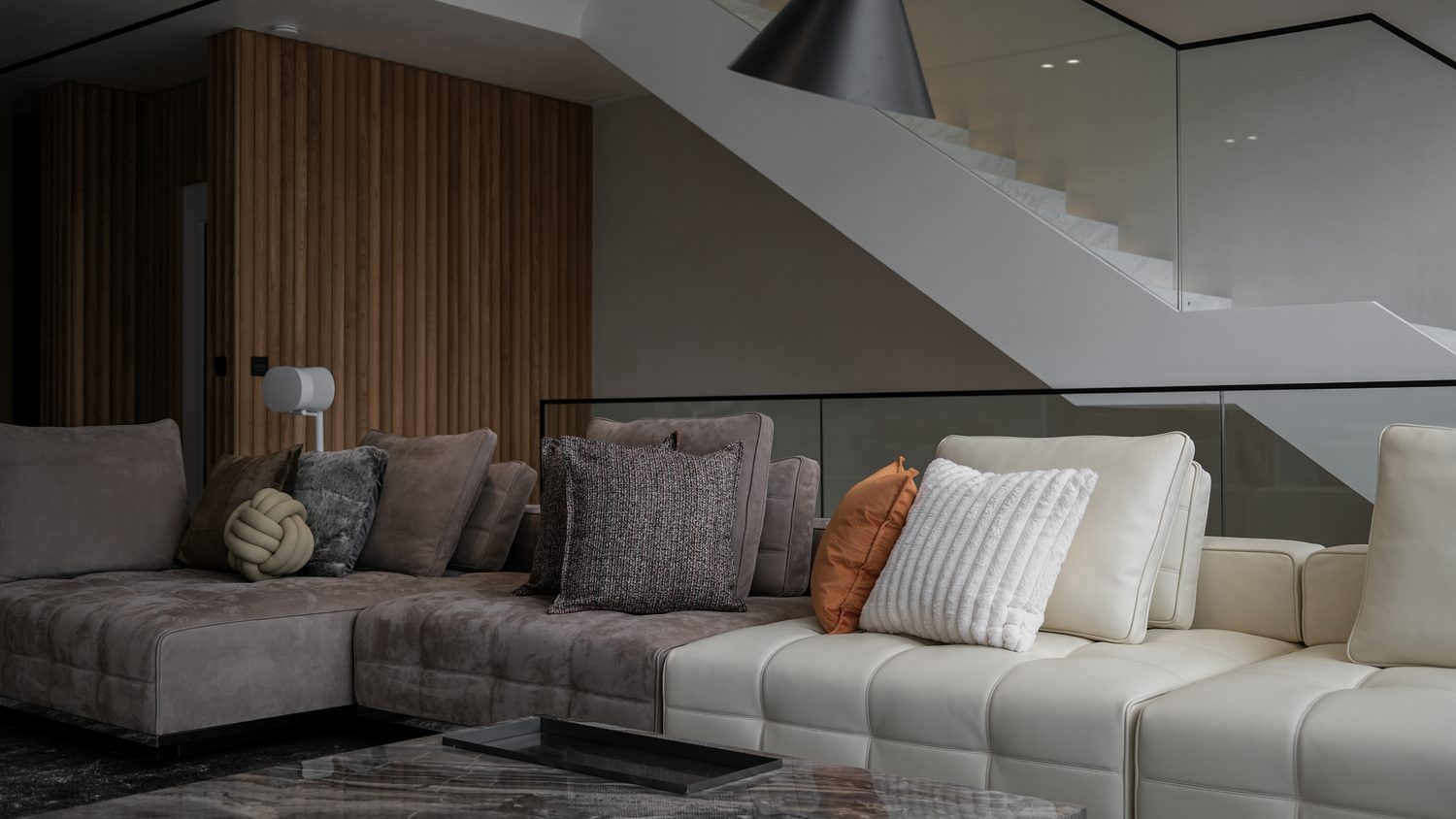 The living room — suede and cream-leather modular sofas below a sculptural stair