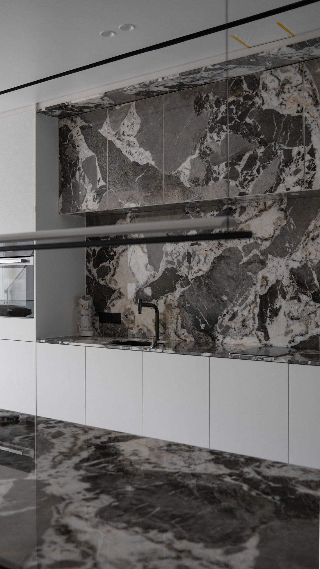 The kitchen seen wider — marble island, splashback and integrated appliances