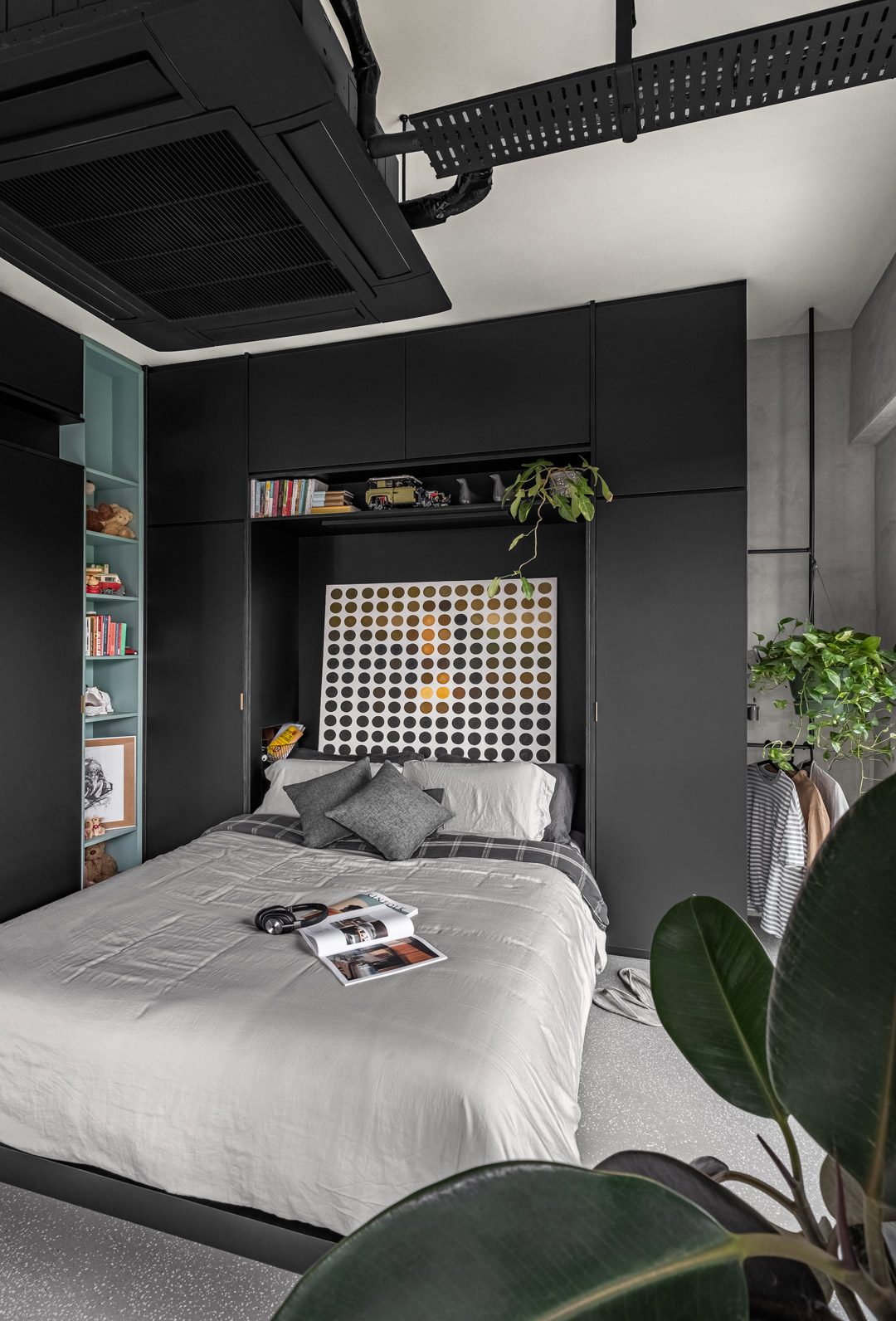 The bedroom in close — the bed nook framed by black cabinetry and a teal niche