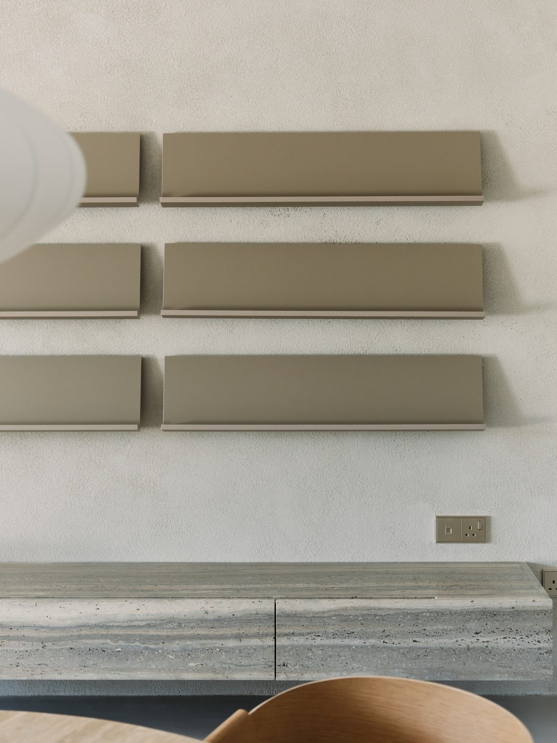 A detail — taupe steel wall shelves above a floating travertine credenza