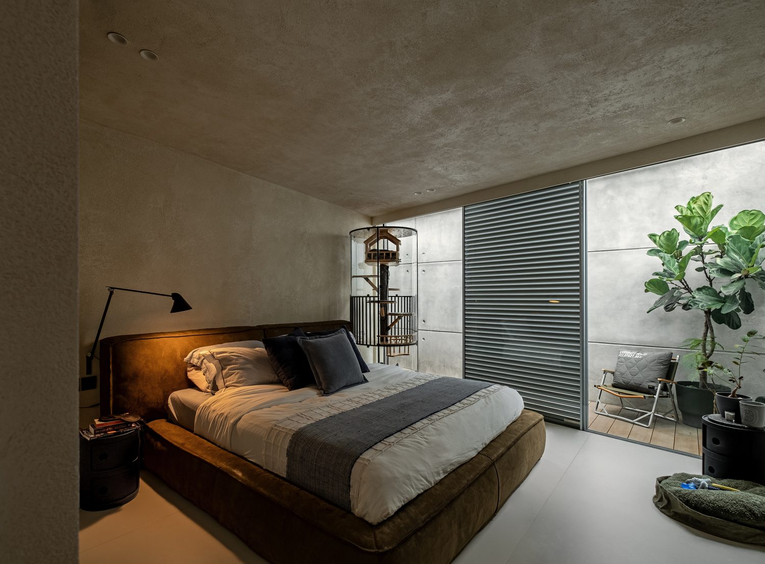 The bedroom — a leather bed under microcement, opening to a planted light well