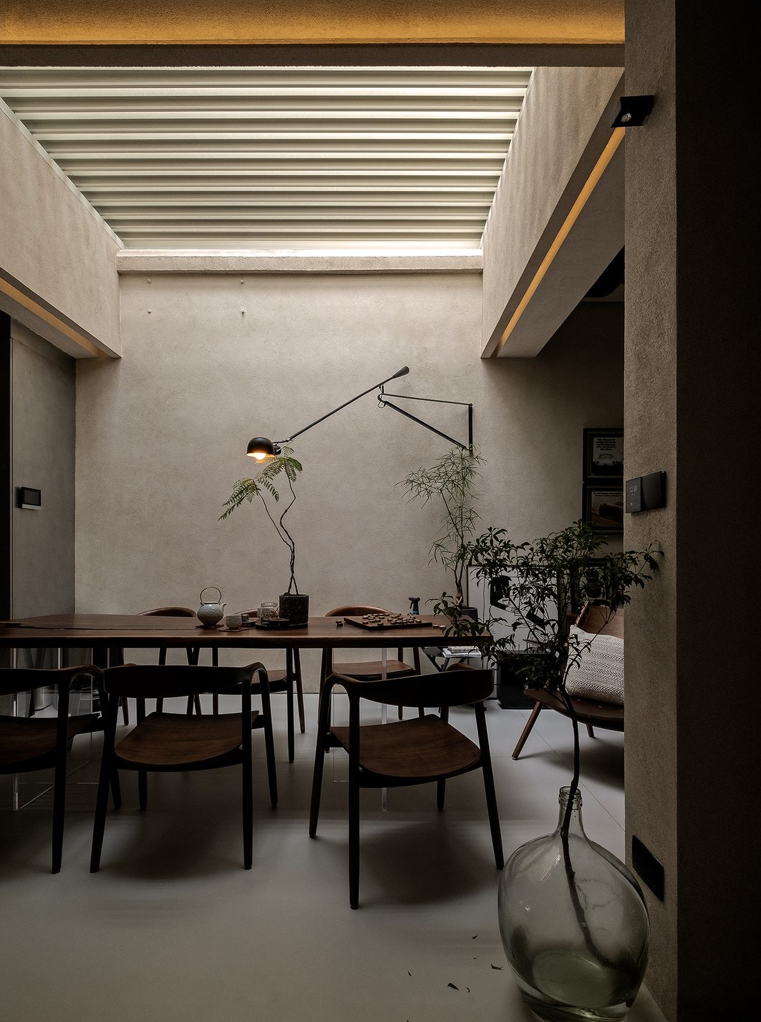 The dining table beneath a louvred skylight, lit by a long cantilever lamp
