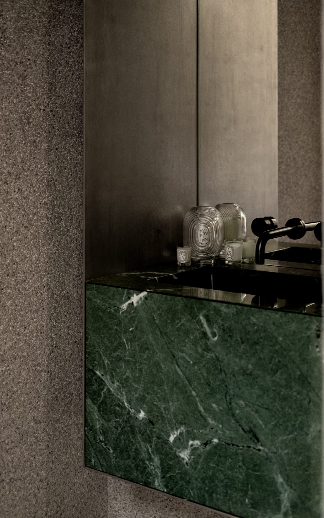 A powder-room vanity in green marble with brushed steel and candles