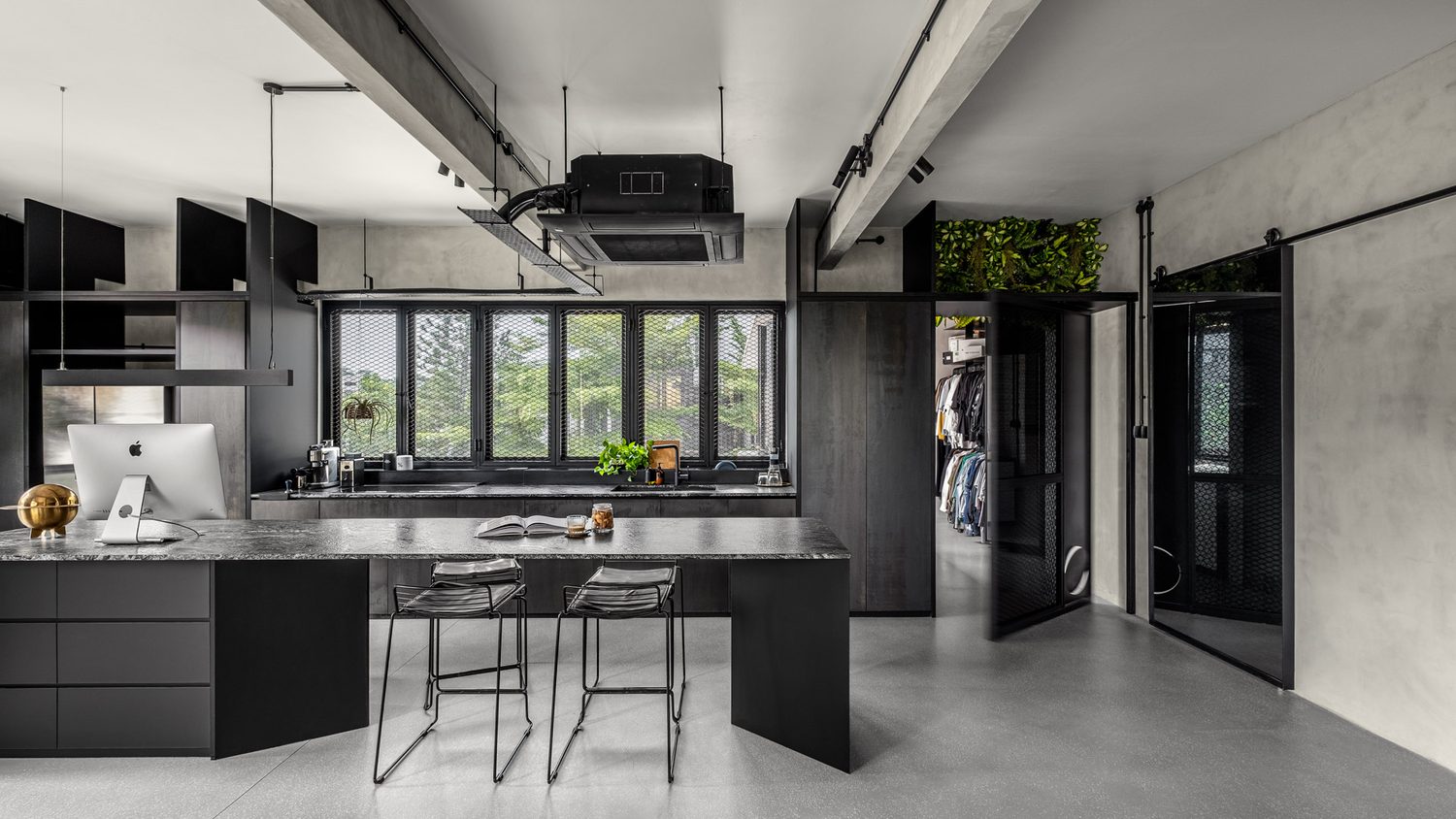 The kitchen — a stone-topped island and steel cabinetry beside a wall of mesh windows