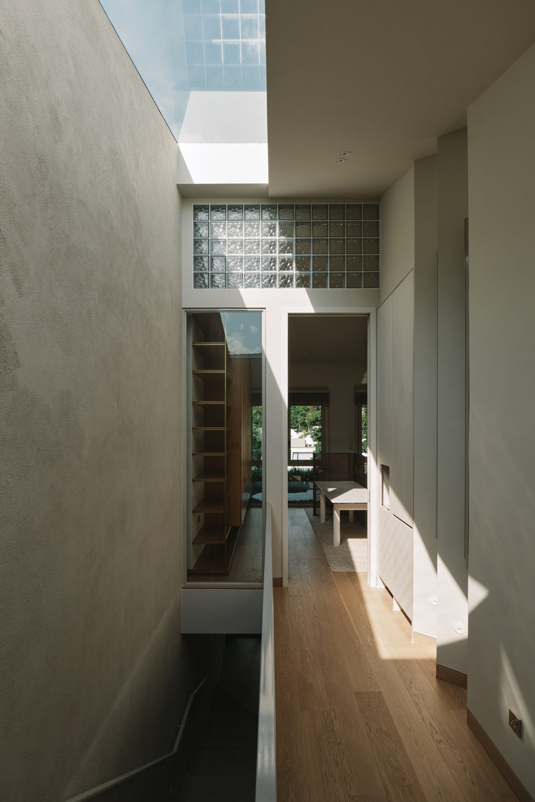 A corridor lit from above, a glass-block clerestory opening to the dining room and garden