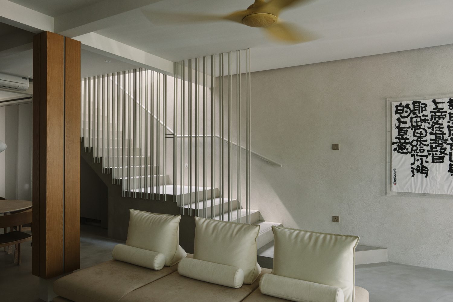 The stair and lounge — the calligraphy scroll on lime plaster in soft afternoon light