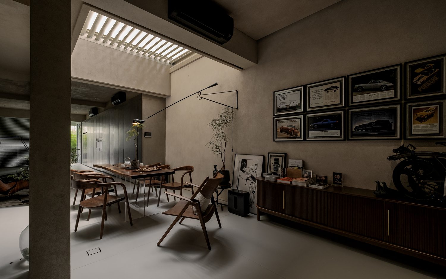 The study — walnut chairs at a glass-legged table below a wall of framed prints