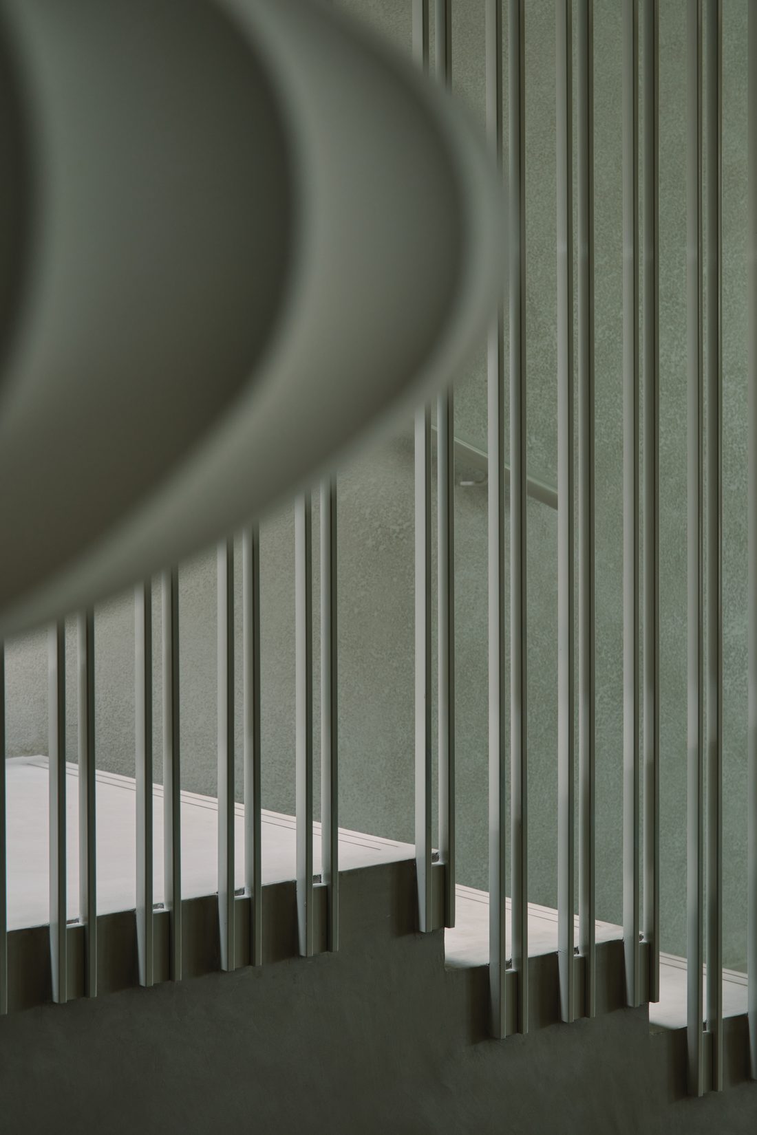 An abstract of the stair balustrade — vertical rods against pale plaster